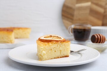 Slice of tasty semolina cake served on white table, closeup