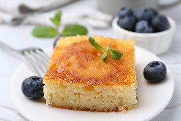 Slice of tasty semolina cake served on white textured table, closeup