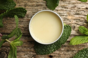 Natural lip balm and mint leaves on wooden background, flat lay