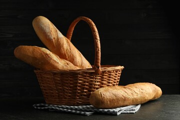Wicker basket with fresh baguettes on black table