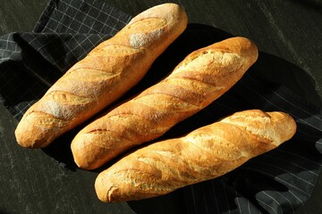 Freshly baked baguettes on black table, flat lay