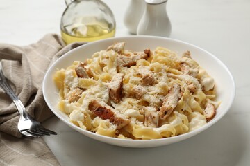 Tasty Alfredo pasta with chicken served on white marble table