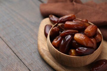 Tasty sweet dried dates in bowl on wooden table, closeup. Space for text