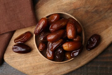 Tasty sweet dried dates in bowl on wooden table, top view