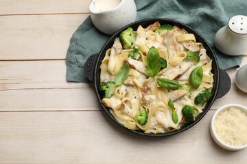 Delicious pasta Alfredo with chicken served on wooden table, flat lay. Space for text