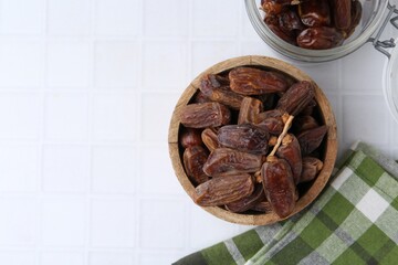 Tasty dried dates on white tiled table, top view. Space for text