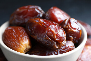 Many tasty dried dates in bowl, closeup