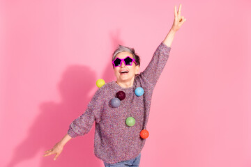 Photo of adorable lovely woman wear jumper holding lights garland showing v-sign empty space isolated pink color background
