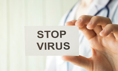 Stop virus text on card and hands holding it. Healthcare or prevention concept.