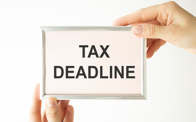 TAXES DEADLINE written on a notebook, hands hold the inscription on a light background. Business and tax concept.