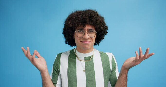 Confused, why and shrug with face of man in studio for thinking, memory and questions. Brainstorming, remember and problem solving with person on blue background for decision, mindset and wondering.