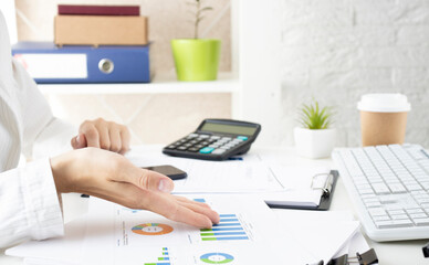 Financial data analyzing hand writing and counting on calculator in office on wood desk