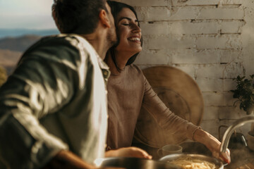 Couple plating spaghetti in a kitchen bathed in warm sunlight