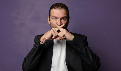 looking serious and displeased with both fingers crossed up front in rejection, asking for silence