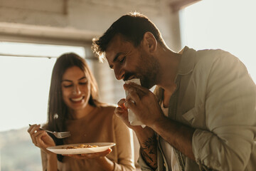 A couple is eating spaghetti in a light-filled kitchen. Romantic lunch at home