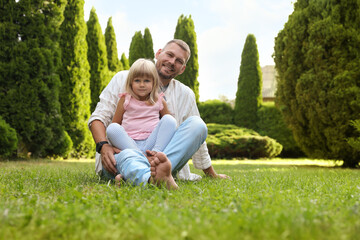 Fototapeta premium Father and his daughter spending time together on green lawn in park