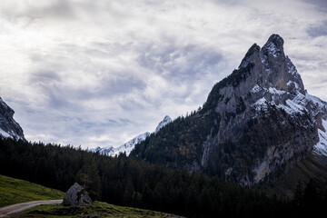 swiss mountains with hiking trail and cloudy sky