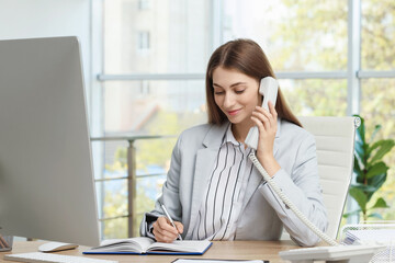 Banker talking on telephone at table in office