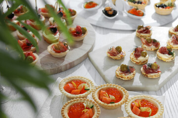 Many different tasty canapes on white wooden table, closeup
