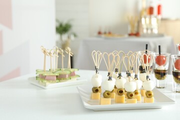 Many different tasty canapes on white table indoors