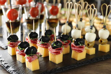 Many different tasty canapes on wooden table, closeup