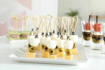 Many different tasty canapes on white table indoors