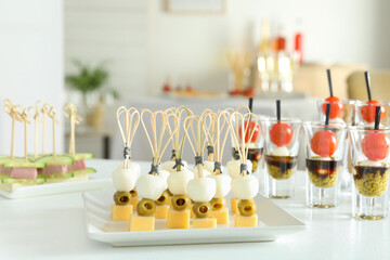Many different tasty canapes on white table indoors