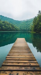 Fototapeta premium A Wooden Pathway to Serenity: A solitary wooden pier extends into a tranquil, mist-shrouded lake surrounded by verdant hills, inviting viewers to find peace and solace in nature's embrace. 