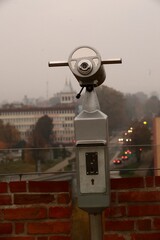 tourist telescope on top of a historical tower with an evening view of the city in the background