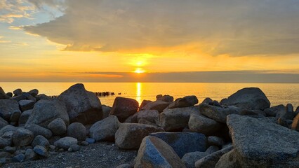 Rocky seashore, golden sun setting into the sea
