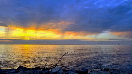 Rocky seashore, golden sun setting into the sea