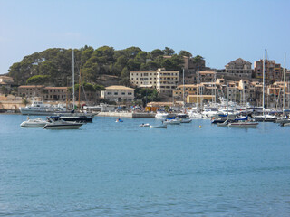 Boats docked at a scenic harbor near a hillside