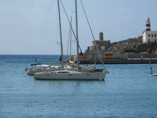 Fototapeta premium Sailboats by lighthouse in harbor