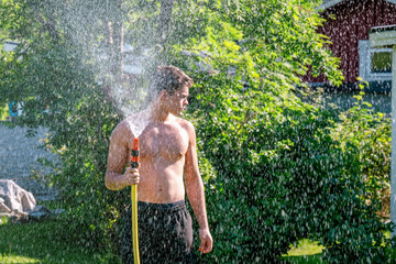 Man watering garden with hose during summer heatwave