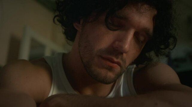 Side closeup of downhearted Caucasian man with stubble indifferently looking around and questioning meaning of life, diving deep into depression, spending time alone