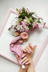 The beautiful hands of a woman with a manicure are holding a bouquet of flowers.
