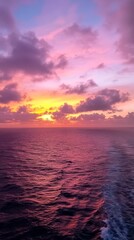 Fototapeta premium Ocean Sunset: A breathtaking sunset paints the sky in vibrant hues of purple, orange, and pink, casting a warm glow over the vast expanse of the ocean.