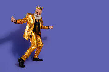 Full body portrait of funny eccentric man enjoy dance empty space golden shiny suit isolated on purple color background