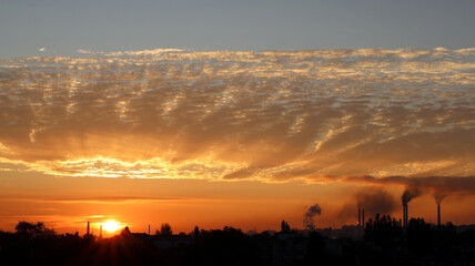 Stunning sunset over an industrial landscape with clouds and smoke in the sky