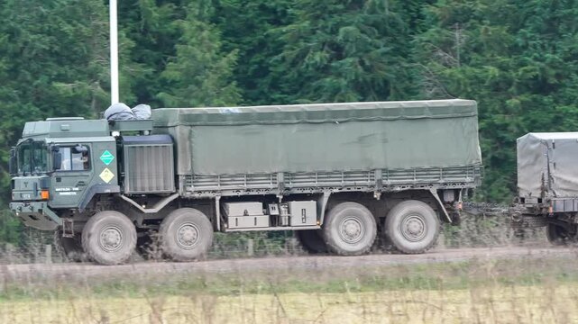 British army MAN HX77 SV 8x8 Heavy Utility Truck towing a trailer along a dirt road
