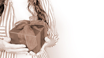 Attractive woman holding a gift box with a red ribbon, on white background. Colour of the year Mocha Mousse