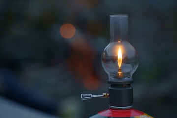 Close-up of a lit camping lantern hanging from a pole in an outdoor setting