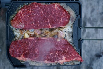 Meat roasting on fire, cooking steak on a pan in nature on a hike