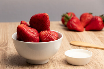 frutillas frescas y maduras servidas listas para comer junto a un pequeño platillo con crema