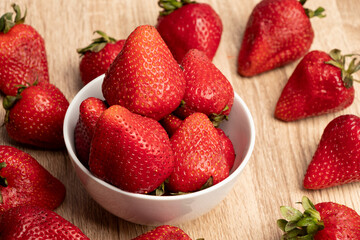 frutillas rojas sobre una mesa y dentro de un plato, vista cenital