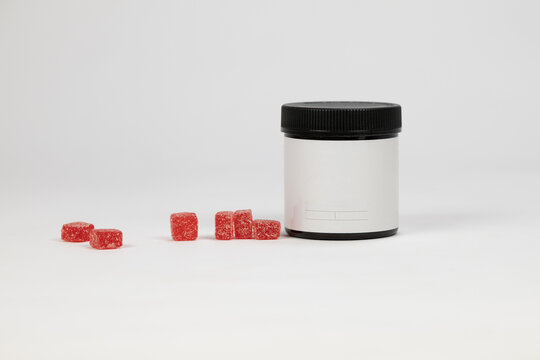 Blank label on amber vitamin gummy jar with red gummies on a white background