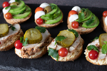 Assortment of bruschetta with baked chicken, cheese, tuna pate, avocado and cherry tomatoes