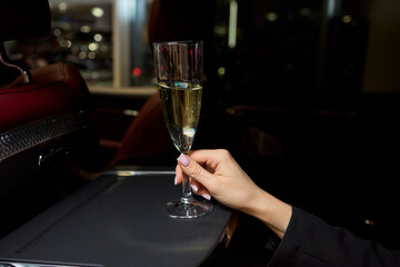 An Elegant Hand Holding a Glass of Exquisite White Wine While in a Luxurious Car Setting