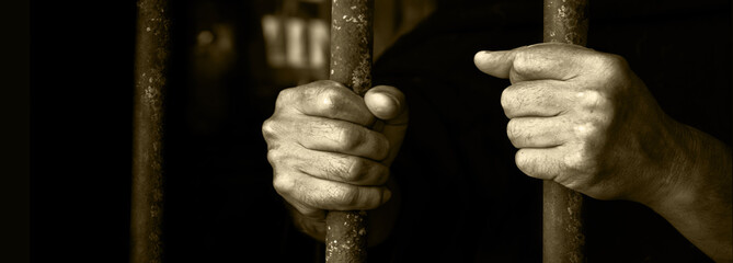 Hands holding the cage of jail