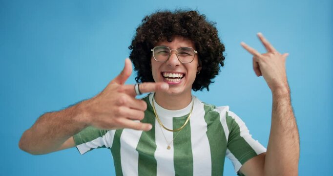 Man, dancing and rocker face with music, rock hands and listening with fun in studio. Happy, style and gen z model with party audio with portrait, smile and excited with blue background and sound